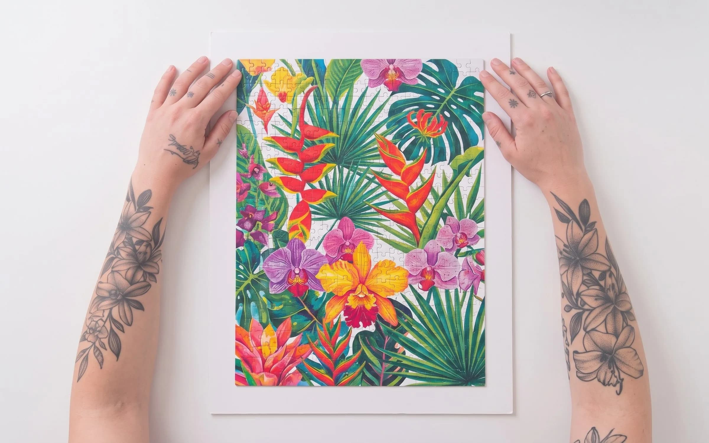 Mãos alinhando o quebra-cabeça floral colado sobre uma placa de papel pluma branco.