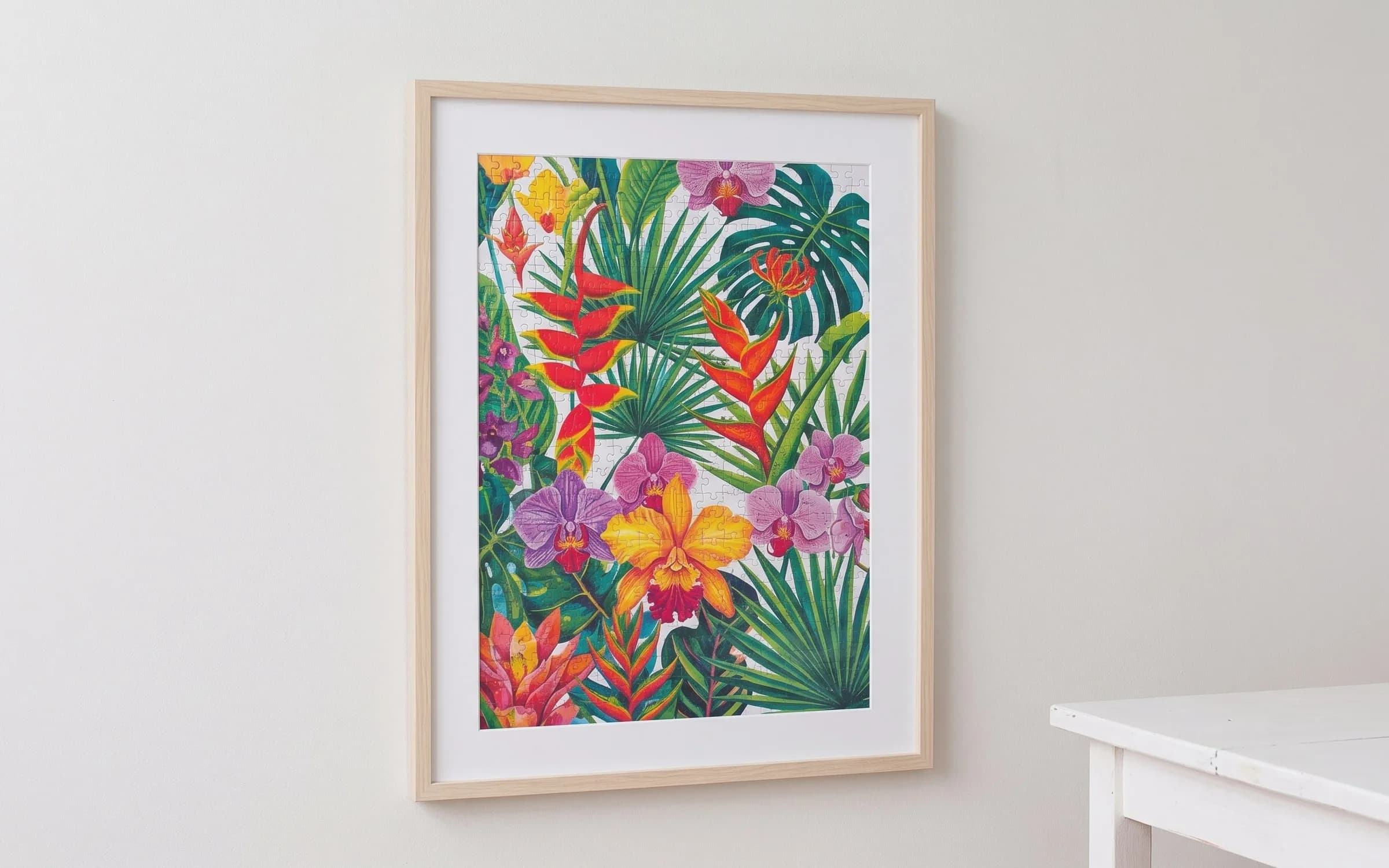 Quebra-cabeça floral emoldurado em madeira clara com paspatur branco, pendurado numa parede.